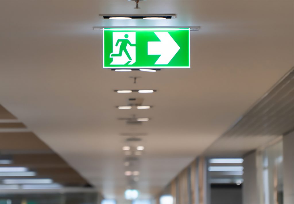 Emergency lighting sign installed by ITC Limited in corridor showing safety and compliance solution
